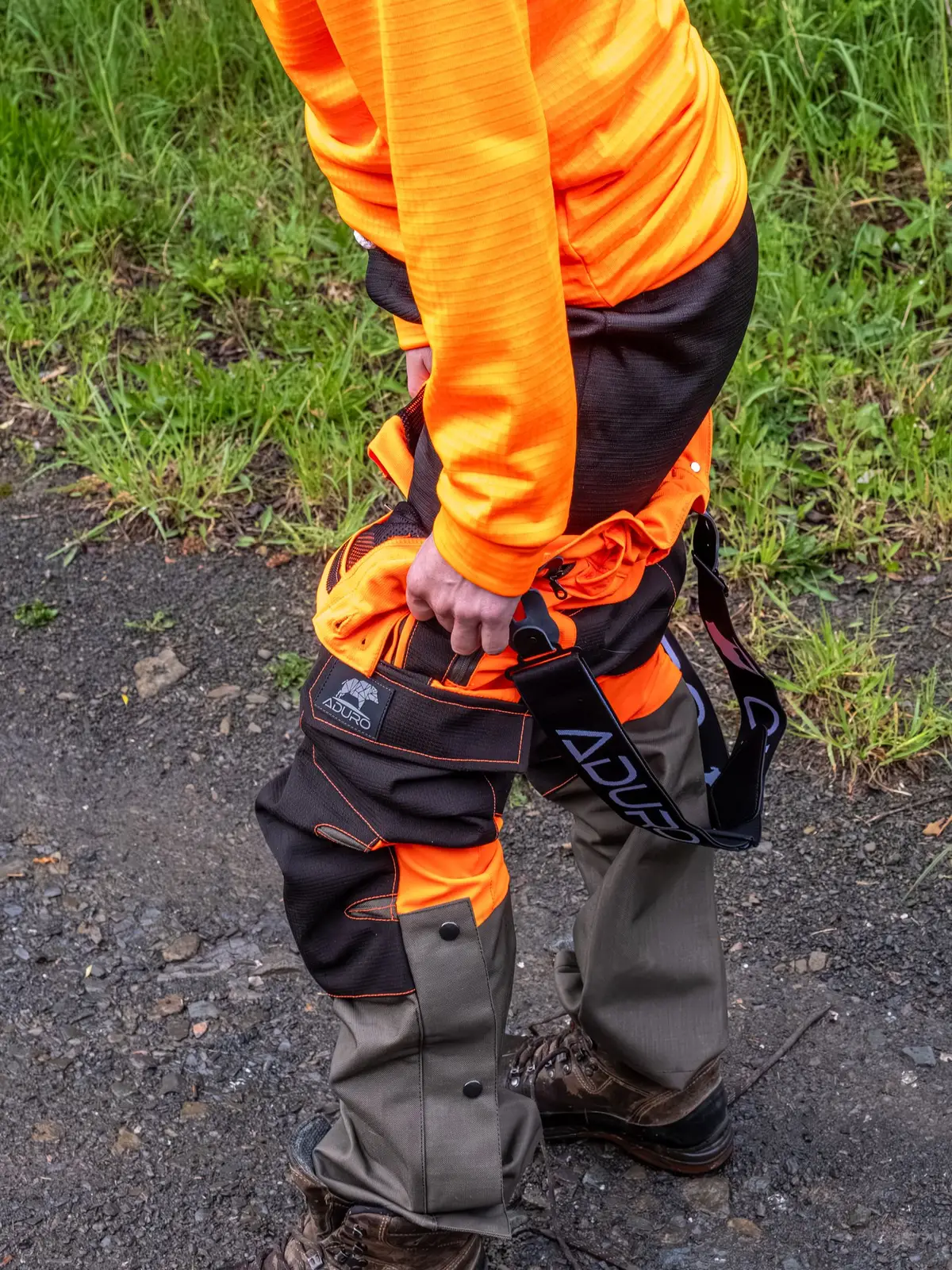 Oberschenkel und Knie der Sau Protect Profi in Orange und Schwarz, Hand am Messer